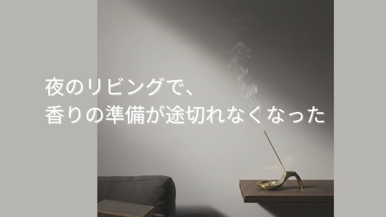 夜のリビングの棚に置かれた真鍮のお香立て。煙がまっすぐ立ち上がり、ソファの端に本が置かれている。